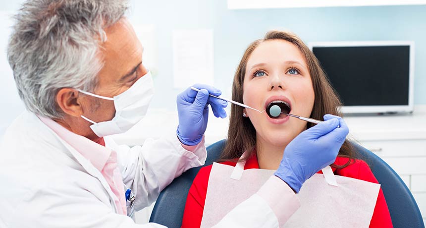 A dentist inspecting a teenagers mouth